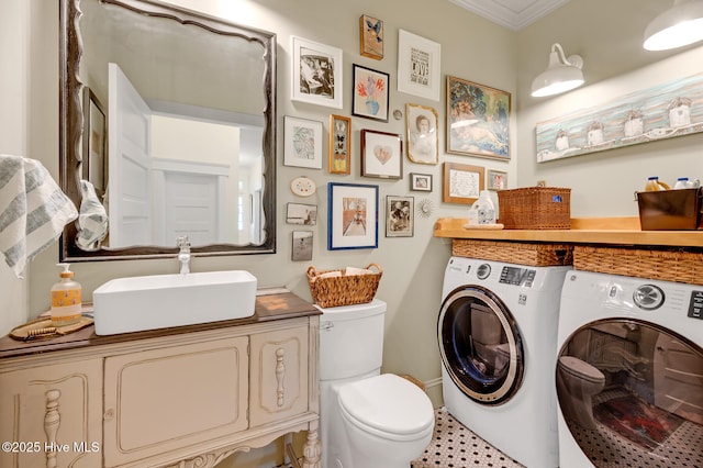 bathroom featuring toilet, ornamental molding, vanity, and washer and clothes dryer