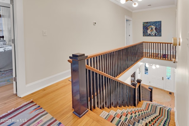 stairs featuring baseboards, a notable chandelier, ornamental molding, and wood finished floors