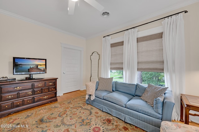 living area with crown molding, ceiling fan, visible vents, and wood finished floors