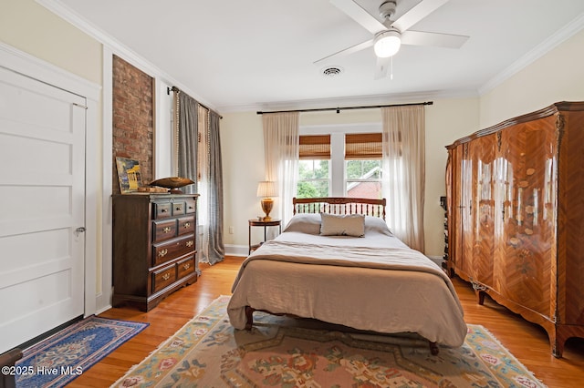bedroom with crown molding, ceiling fan, light wood-type flooring, and visible vents