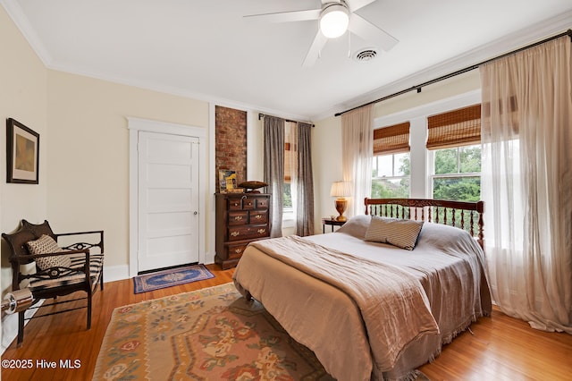 bedroom with a ceiling fan, baseboards, ornamental molding, light wood finished floors, and visible vents