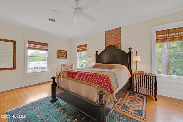 bedroom with baseboards, crown molding, visible vents, and wood finished floors