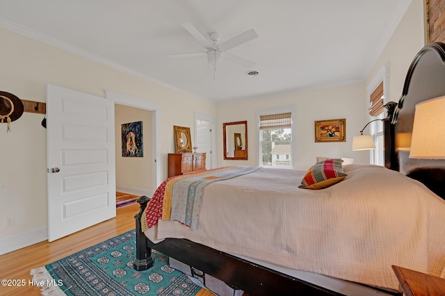 bedroom with wood finished floors, ornamental molding, visible vents, a ceiling fan, and baseboards