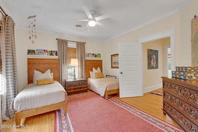 bedroom featuring wood finished floors, ornamental molding, visible vents, a ceiling fan, and baseboards