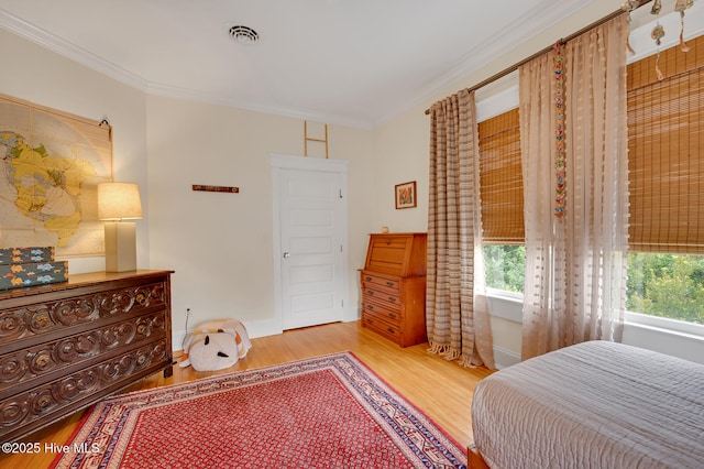 bedroom featuring multiple windows, ornamental molding, and wood finished floors