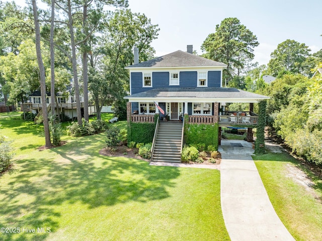 view of front of property with covered porch, a shingled roof, a front yard, driveway, and stairs
