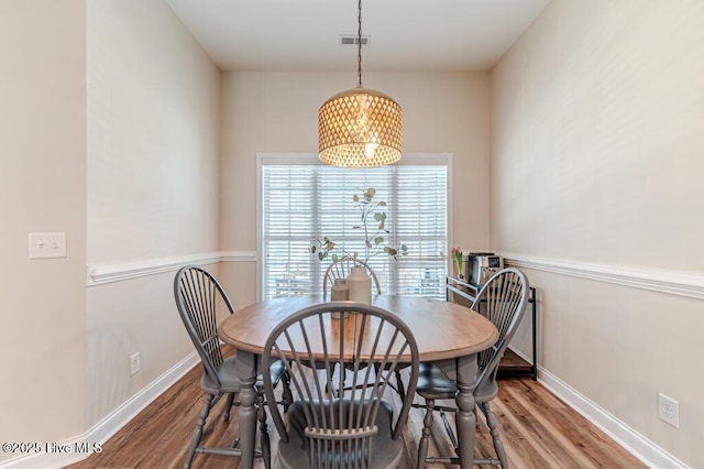 dining space featuring wood finished floors, baseboards, and a chandelier