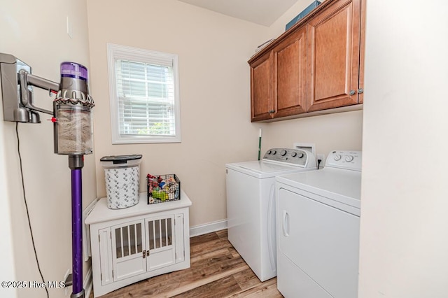laundry area featuring washer and clothes dryer, cabinet space, light wood-style flooring, and baseboards