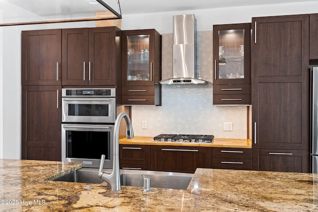 4145 Brighton Ln, Southport, NC 28461 - kitchen featuring stainless steel appliances, backsplash, dark brown cabinets, and wall chimney exhaust hood