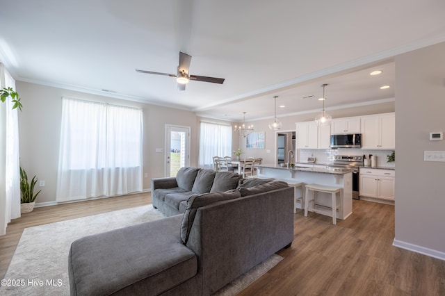 4524 Sweet Williams Ln NW, Wilson, NC 27896 - living room featuring light wood-style flooring, crown molding, and ceiling fan with notable chandelier