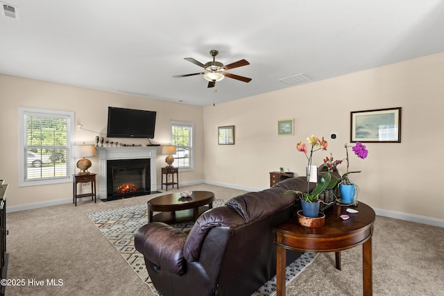 living area with carpet flooring, ceiling fan, a fireplace with flush hearth, and baseboards