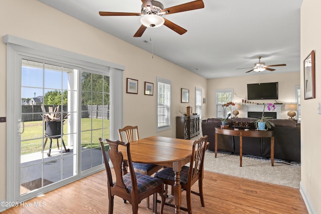 324 Catamaran Rd, Swansboro, NC 28584 - dining room featuring a ceiling fan, light wood finished floors, and a fireplace