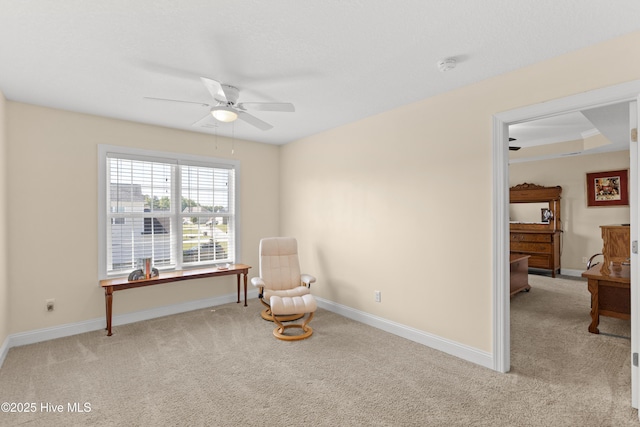 living area featuring light colored carpet, a ceiling fan, and baseboards