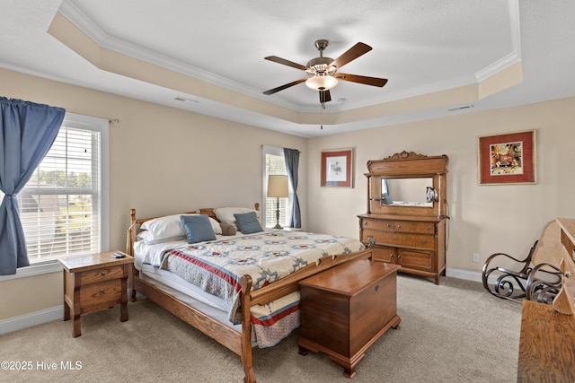 bedroom featuring a tray ceiling, light colored carpet, crown molding, baseboards, and a ceiling fan