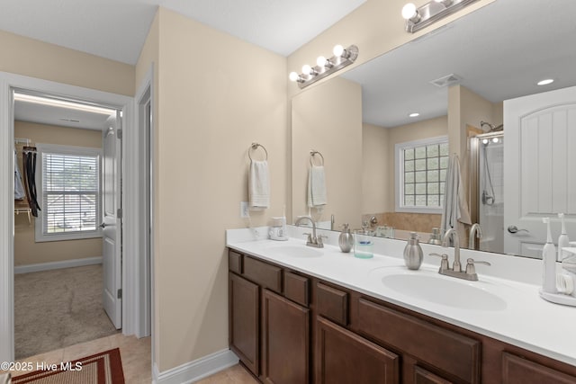 bathroom with a stall shower, double vanity, tile patterned floors, and baseboards