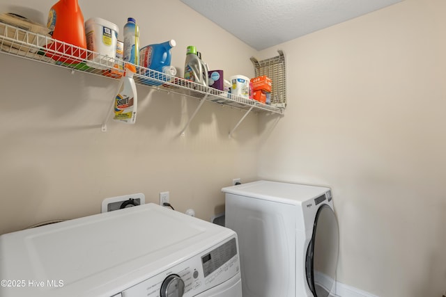 clothes washing area with washer and dryer, a textured ceiling, and baseboards