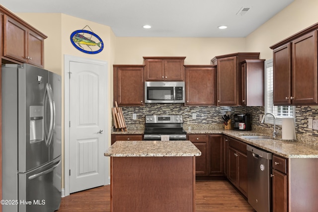 kitchen with stainless steel appliances, a sink, dark wood-type flooring, and tasteful backsplash