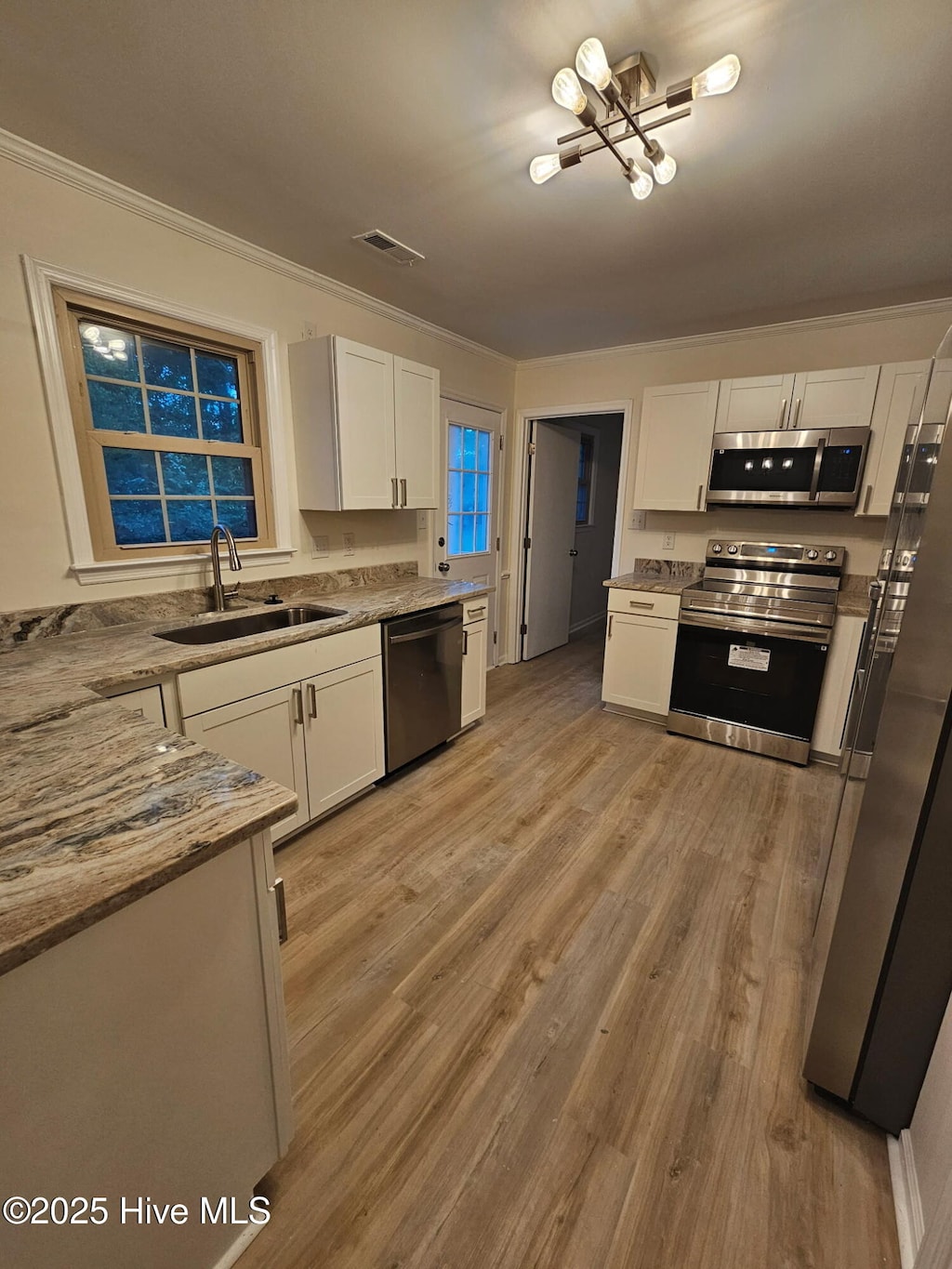 kitchen with white cabinets, stainless steel appliances, visible vents, and a sink