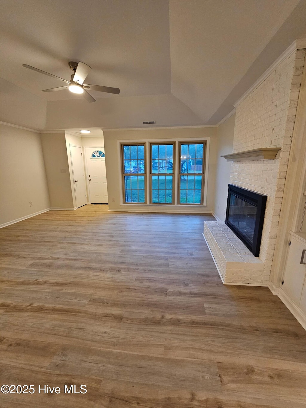 unfurnished living room featuring wood finished floors, visible vents, vaulted ceiling, a fireplace, and a ceiling fan