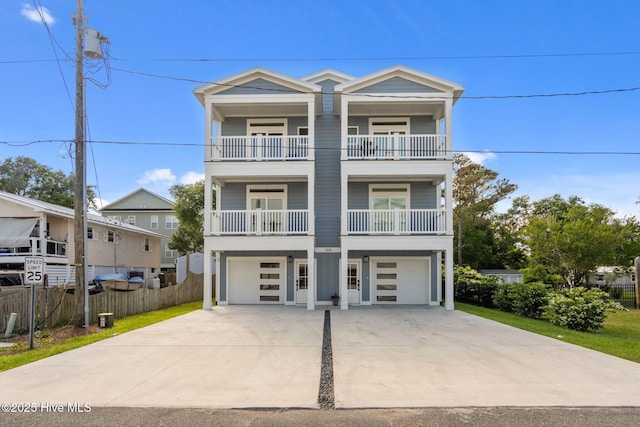 raised beach house with fence, a garage, concrete driveway, and a balcony