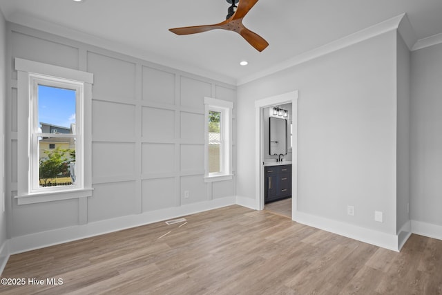 unfurnished bedroom with ensuite bathroom, visible vents, a decorative wall, crown molding, and light wood-style floors
