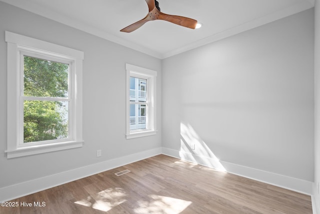 empty room featuring baseboards, a wealth of natural light, ornamental molding, and visible vents