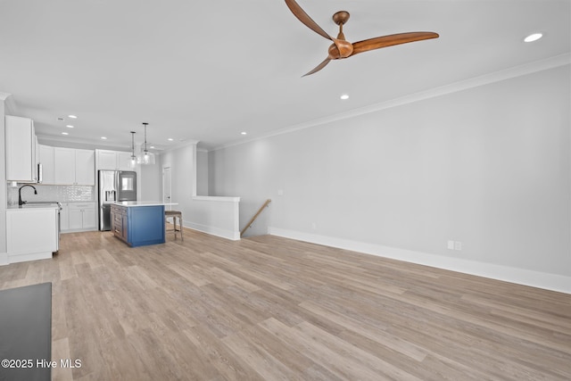 unfurnished living room with light wood finished floors, a ceiling fan, a sink, ornamental molding, and recessed lighting