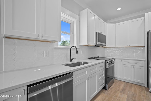 kitchen featuring a sink, light wood-style floors, white cabinetry, light countertops, and appliances with stainless steel finishes