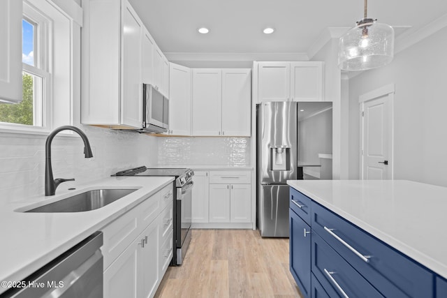 kitchen with light countertops, stainless steel appliances, a sink, and blue cabinetry