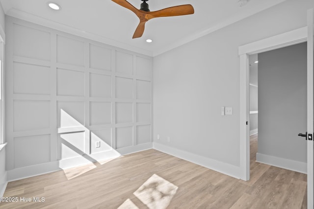 unfurnished bedroom featuring light wood-type flooring, baseboards, a decorative wall, and recessed lighting