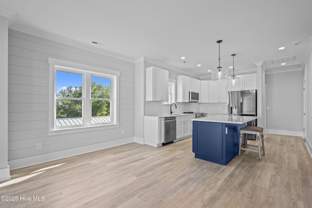 kitchen featuring stainless steel appliances, white cabinetry, a kitchen bar, light countertops, and light wood-style floors