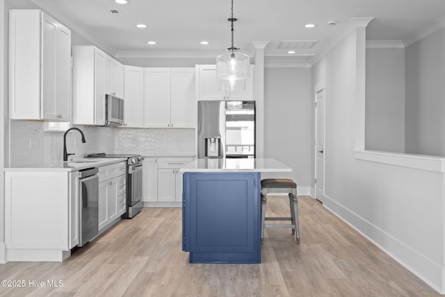 kitchen featuring a breakfast bar, a sink, stainless steel appliances, crown molding, and light countertops
