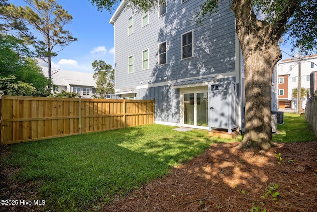 rear view of property featuring a yard and fence