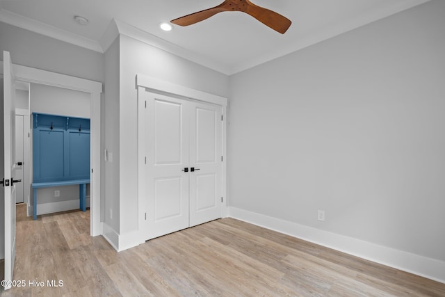 unfurnished bedroom with a ceiling fan, a closet, baseboards, ornamental molding, and wood finished floors