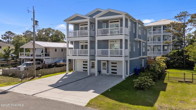view of front of house featuring fence, an attached garage, a balcony, concrete driveway, and a front yard