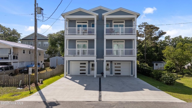 view of front facade featuring concrete driveway, fence, a garage, and a balcony