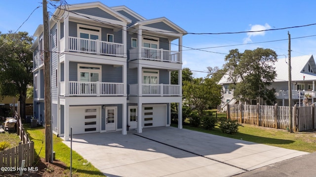 view of front facade featuring fence, an attached garage, concrete driveway, and a balcony