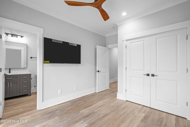 unfurnished bedroom with a closet, light wood-type flooring, baseboards, and a sink