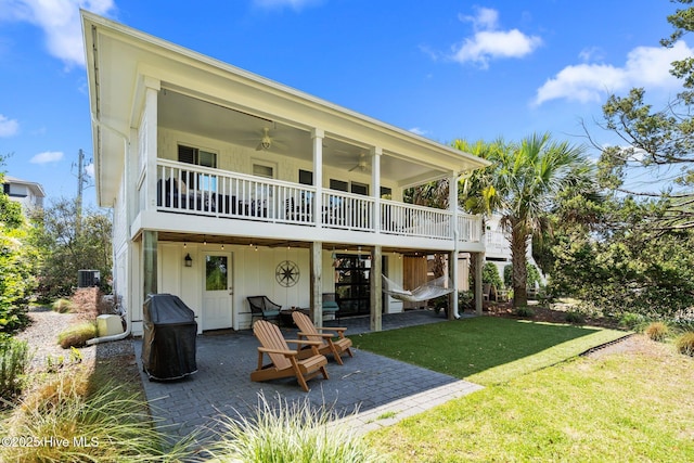 rear view of house with a ceiling fan, a patio area, a yard, a wooden deck, and central AC