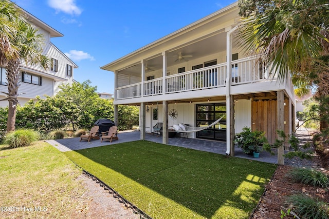 back of property featuring a patio, ceiling fan, board and batten siding, and a yard