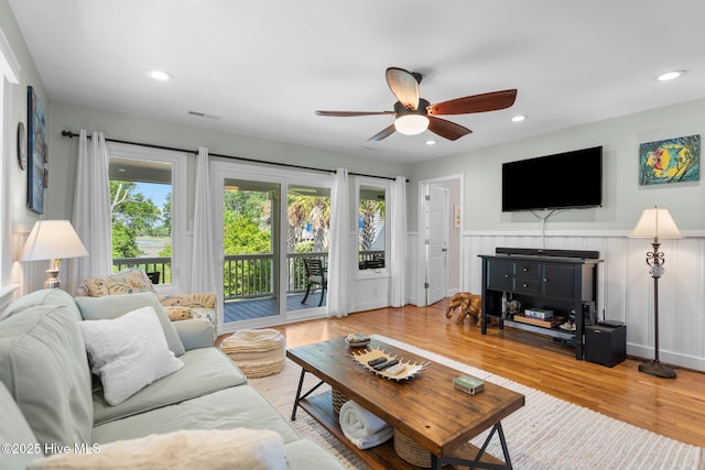 living area featuring ceiling fan, healthy amount of natural light, a wainscoted wall, wood finished floors, and recessed lighting