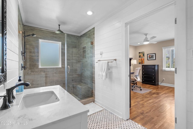 bathroom with ornamental molding, a shower stall, ceiling fan, baseboards, and wood finished floors