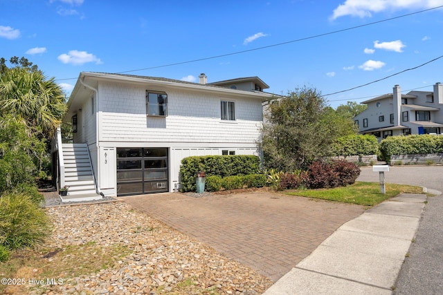 view of front of house with decorative driveway, an attached garage, and stairs