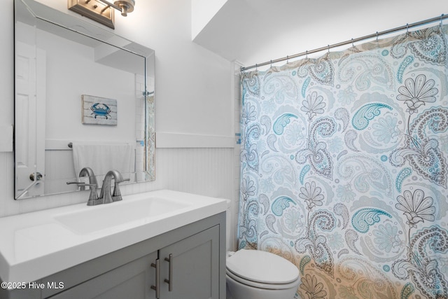 bathroom featuring a wainscoted wall, toilet, vanity, and a shower with shower curtain