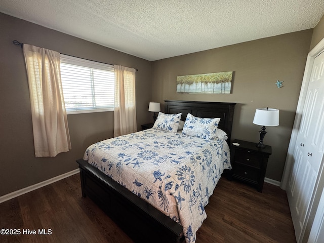 bedroom with dark wood-type flooring, baseboards, and a textured ceiling