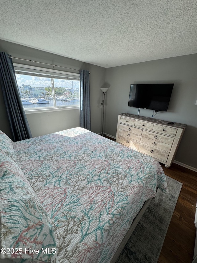 bedroom with dark wood finished floors, a textured ceiling, and baseboards