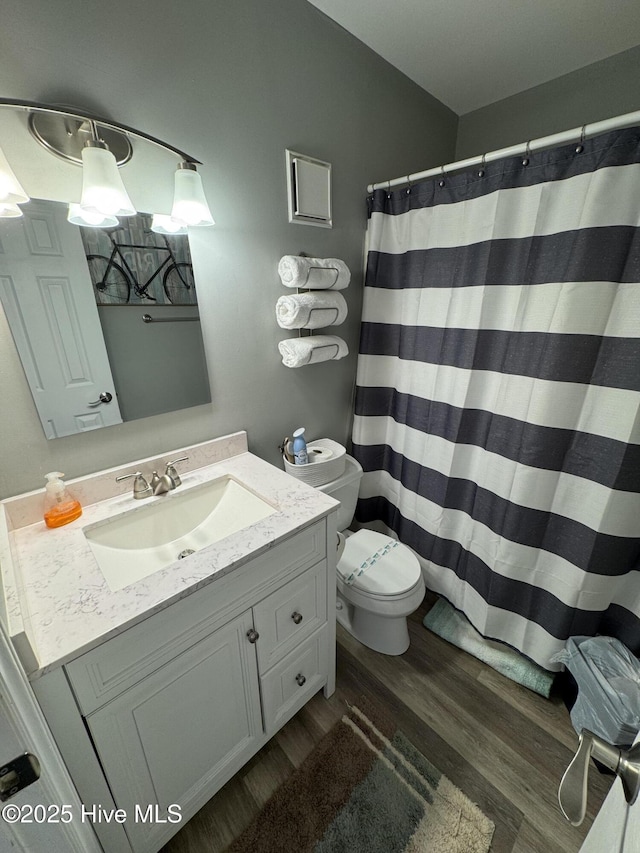 bathroom featuring wood finished floors, vanity, toilet, and a shower with curtain