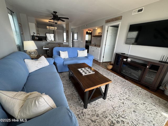 living area with wood finished floors, ceiling fan, and healthy amount of natural light