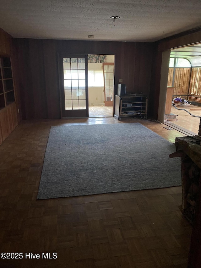 unfurnished living room featuring wooden walls and plenty of natural light