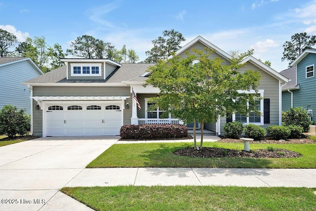 view of front facade featuring an attached garage, a porch, driveway, a front yard, and roof with shingles